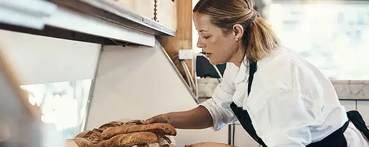 person working at restaurant placing bread